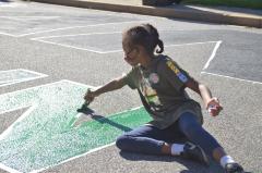Young girl painting a green "N" for the Black Lives Matter street mural