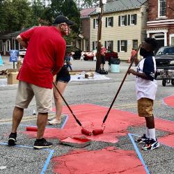 Mayor Chris Cerino painting the Black Lives Matter street mural with a young boy