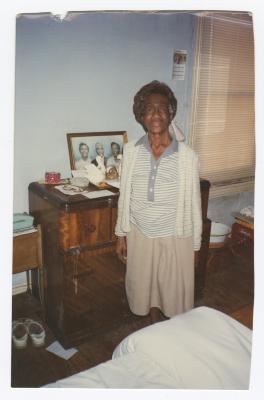 Elderly woman standing next to dresser