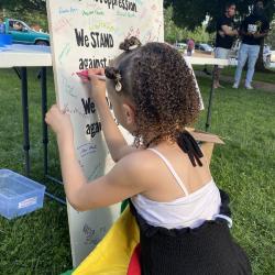 Young girl signing the Community Commitment Mural