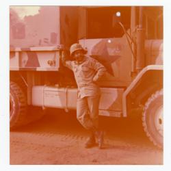 Sergeant Roy D. Thomas, Jr. leaning on a large vehicle