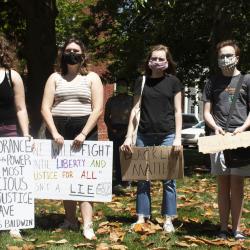 Four young adult protesters with signs