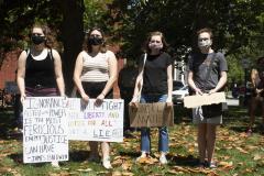 Four young adult protesters with signs